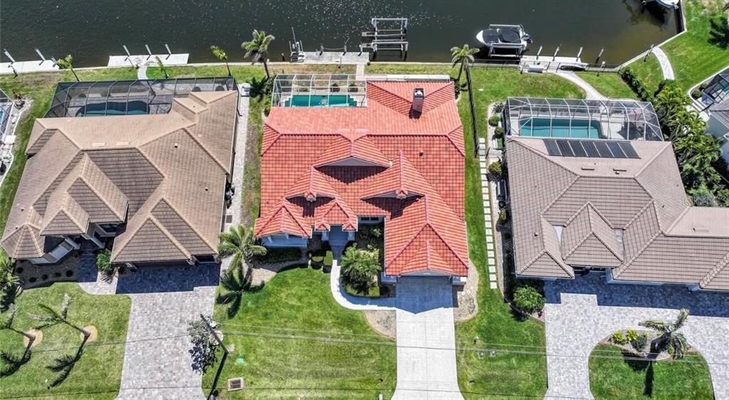 An aerial view shows three waterfront houses with tiled roofs, swimming pools, and private docks — 341 SEGOVIA DRIVE, PUNTA GORDA, FL