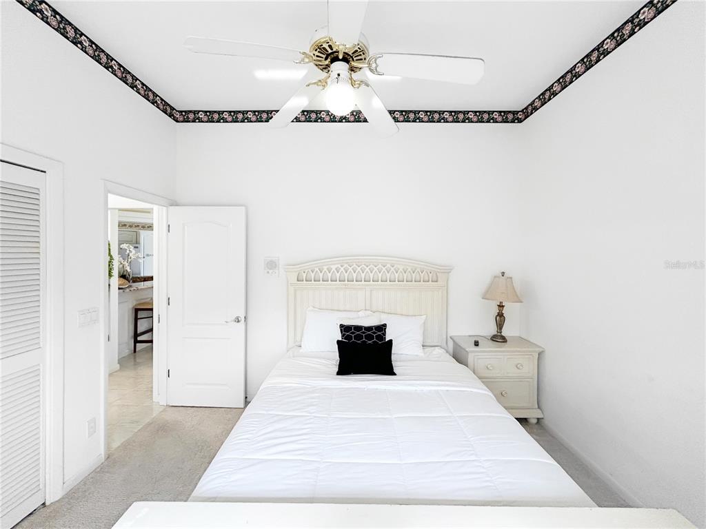 A bedroom features a white bed, a ceiling fan, and a floral wallpaper border — 341 SEGOVIA DRIVE, PUNTA GORDA, FL