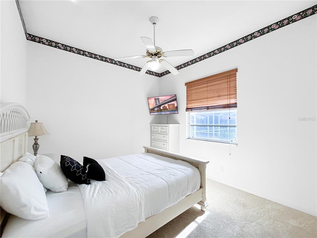 A bedroom features a white bed, a ceiling fan, a dresser with a television, and wallpaper — 341 SEGOVIA DRIVE, PUNTA GORDA, FL