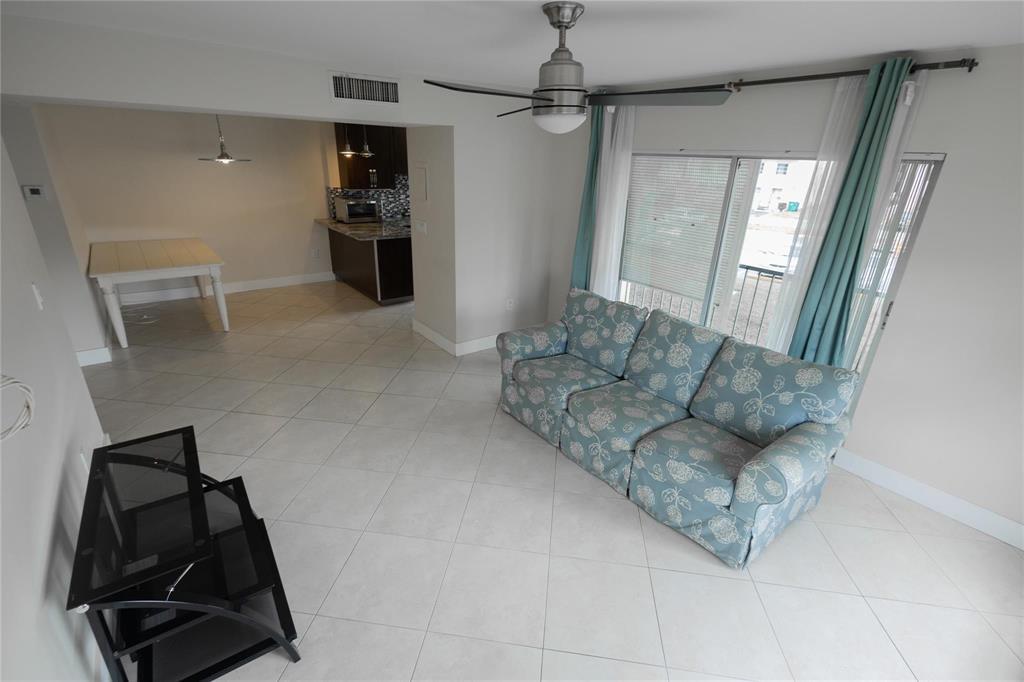 A living room with a floral sofa, tile floors, and an adjacent dining area and kitchen — 4152 Inverrary Drive # 202, Lauderhill FL 33319, LAUDERHILL, FL