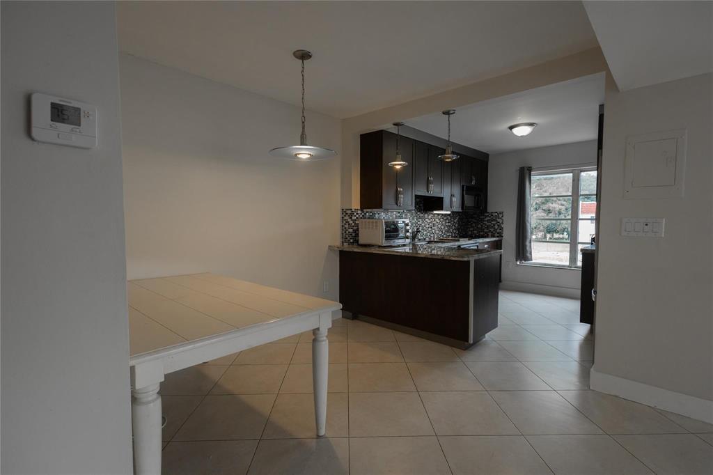 A kitchen with dark cabinets and a breakfast bar sits adjacent to a dining area — 4152 Inverrary Drive # 202, Lauderhill FL 33319, LAUDERHILL, FL