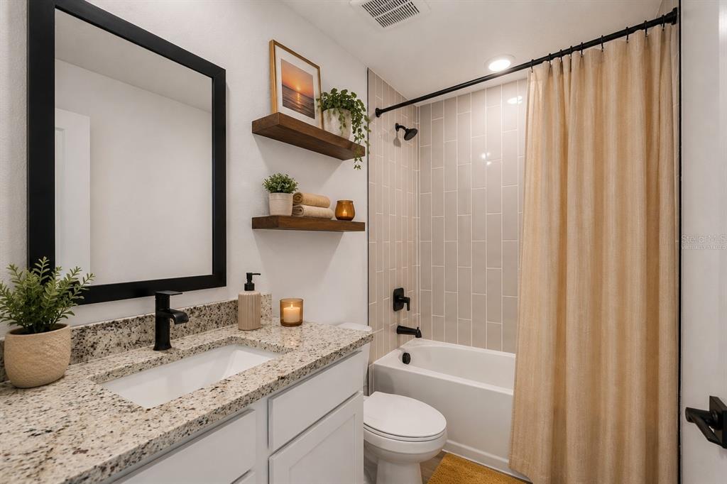 A bathroom features a granite vanity, black fixtures, open wood shelving, and a tiled shower — 12143 ELSTON STREET, SPRING HILL, FL