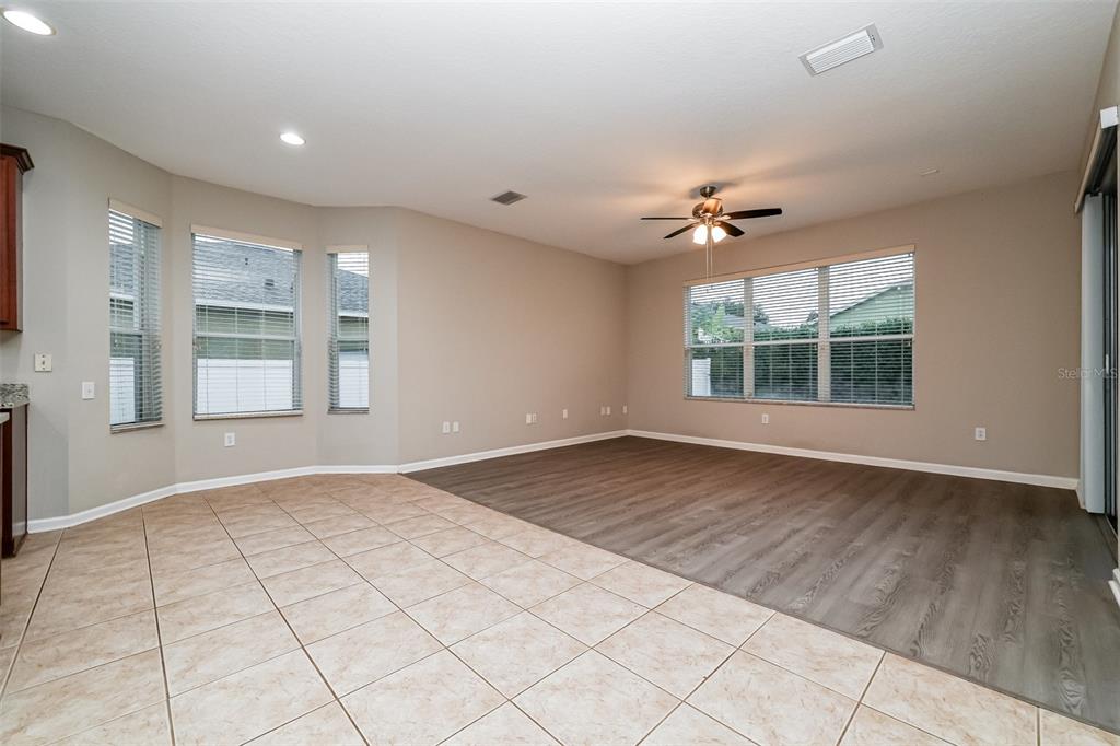 An open-concept living area features a tiled kitchen space transitioning into a wood-floored living room — 2026 HEARTLAND CIRCLE, VALRICO, FL