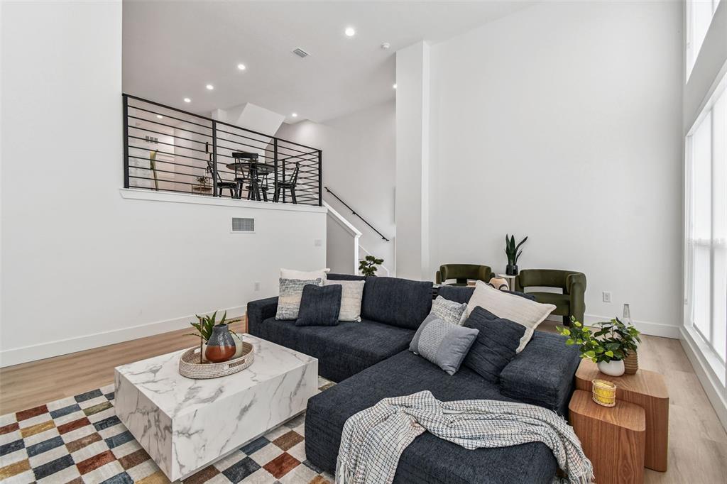 A living room features a dark sectional sofa, marble coffee table, and a lofted dining area — 3840 POMPANO DRIVE SE, ST PETERSBURG, FL