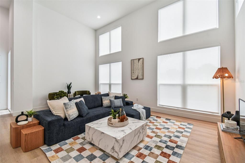 A living room features a blue sectional sofa, a marble coffee table, and tall windows — 3840 POMPANO DRIVE SE, ST PETERSBURG, FL