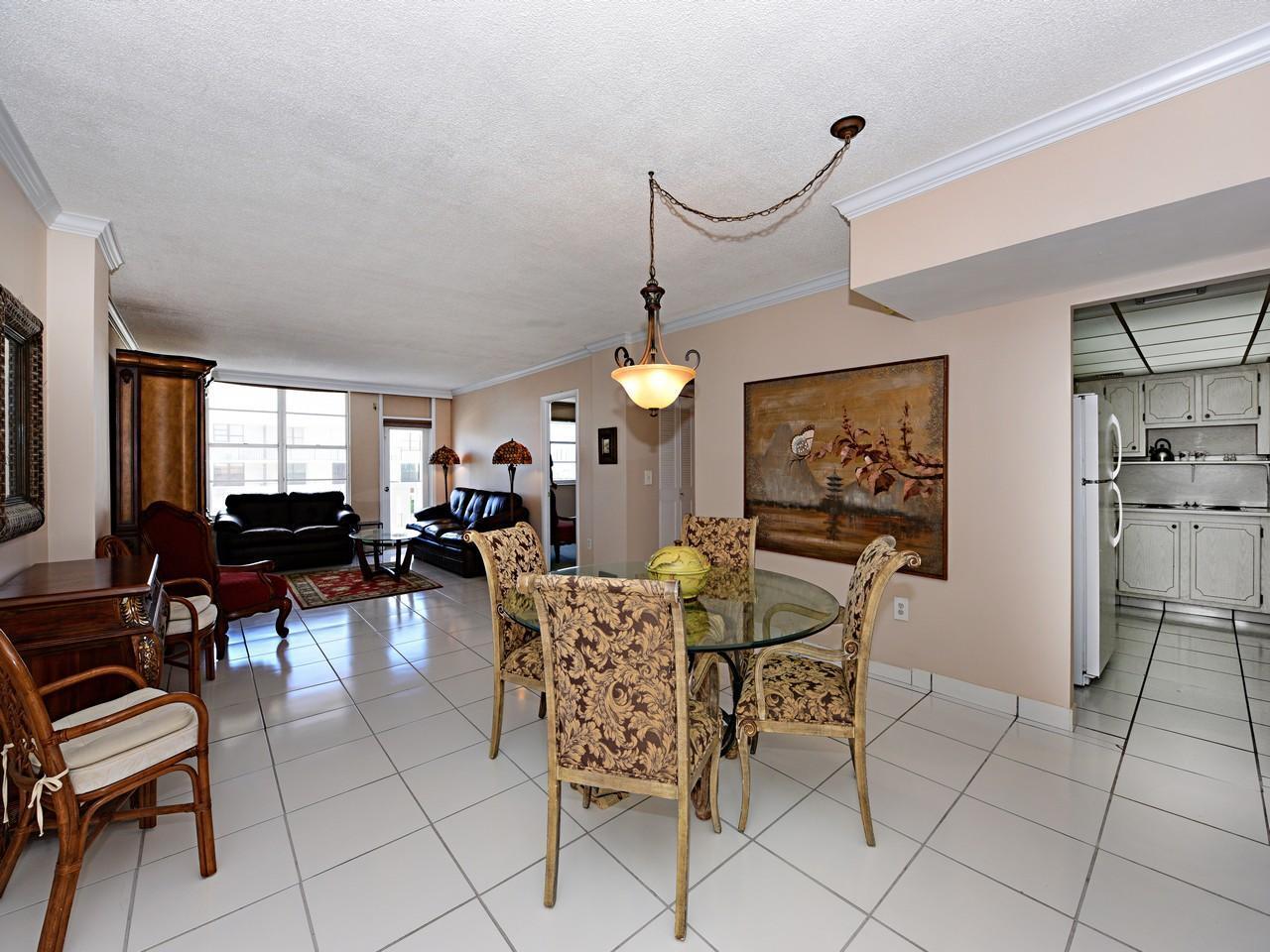 A dining area with a glass table and chairs sits next to a living room — 3450 S Ocean Boulevard # 621, Palm Beach FL 33480, PALM BEACH, FL
