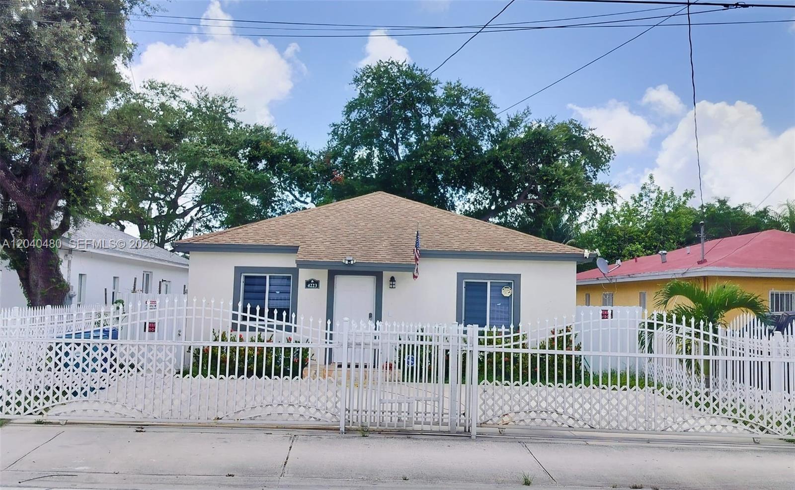 A single-story house with a white exterior, gray trim, and a white metal fence — 4223 NW 32nd Ave, Miami FL 33142, MIAMI, FL