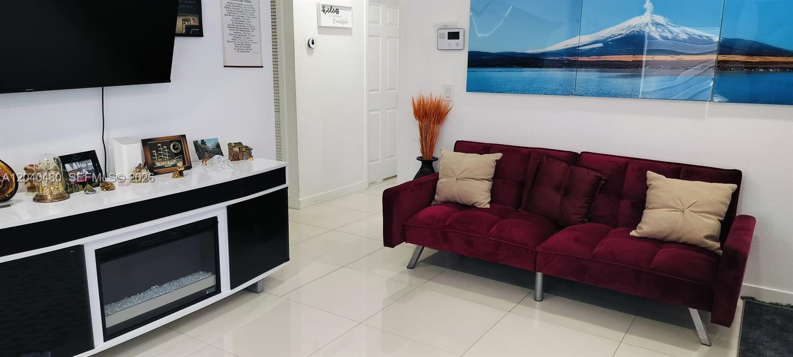 A living room features a burgundy sofa, a fireplace media console, and a mountain landscape mural — 4223 NW 32nd Ave, Miami FL 33142, MIAMI, FL