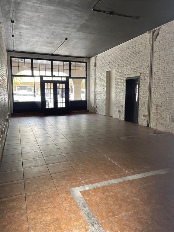 An empty commercial space features white brick walls, a dark ceiling, and tiled flooring — 1031 NEW YORK AVENUE, ST CLOUD, FL