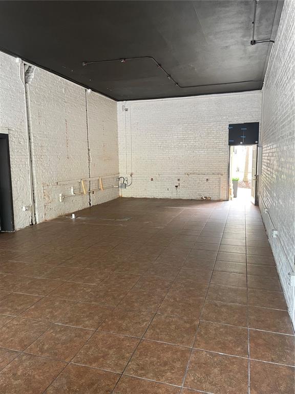 An empty commercial space with white brick walls, a black ceiling, and brown tiled floors — 1031 NEW YORK AVENUE, ST CLOUD, FL