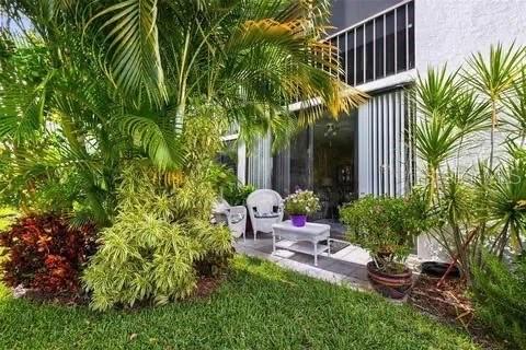 A patio area features white wicker furniture, potted plants, and lush landscaping outside a building — 2424 W TAMPA BAY BOULEVARD UNIT L105, TAMPA, FL