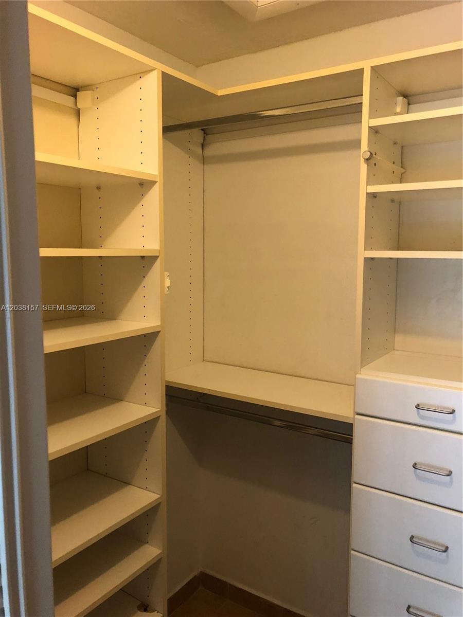 A walk-in closet features white shelving, a hanging rod, and a stack of drawers — 3808 SW 79th Ave # 63, Miami FL 33155, MIAMI, FL
