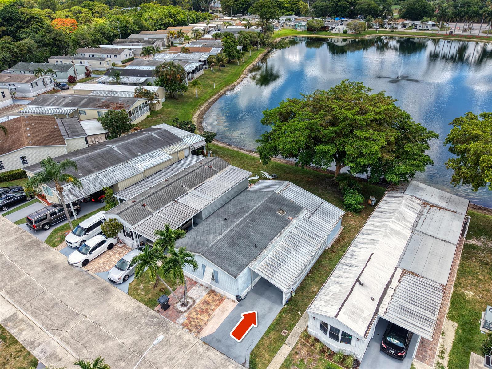 An aerial view shows a light blue manufactured home with a carport and driveway — 141 Plantation Boulevard, Lake Worth FL 33467, LAKE WORTH, FL