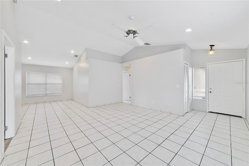 An empty room with white tiled floors, a vaulted ceiling, and a ceiling fan — 9752 PINEY POINT CIRCLE, ORLANDO, FL