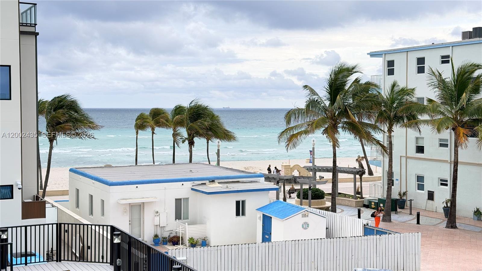 An elevated view of a beach, palm trees, and nearby buildings under a cloudy sky — 321 Wilson St # A105, Hollywood FL 33019, HOLLYWOOD, FL