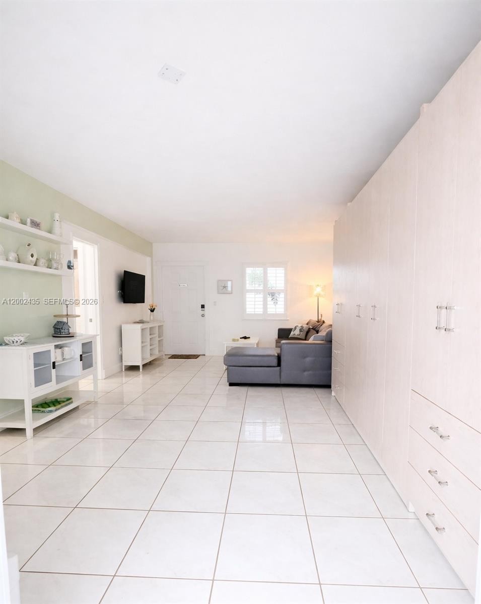 A living room features white tile floors, a grey sectional sofa, and built-in wall cabinetry — 321 Wilson St # A105, Hollywood FL 33019, HOLLYWOOD, FL