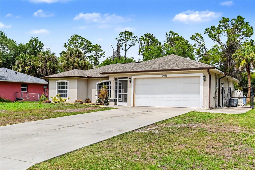 A single-story house with a beige exterior, a two-car garage, and a concrete driveway — 2638 ASHLAND LANE, NORTH PORT, FL