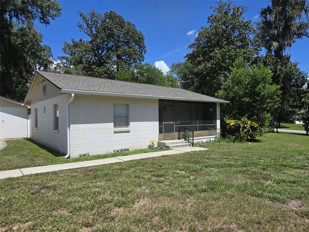 A single-story white concrete block house with a screened front porch and a concrete walkway — 659 N KEPLER ROAD, DELAND, FL