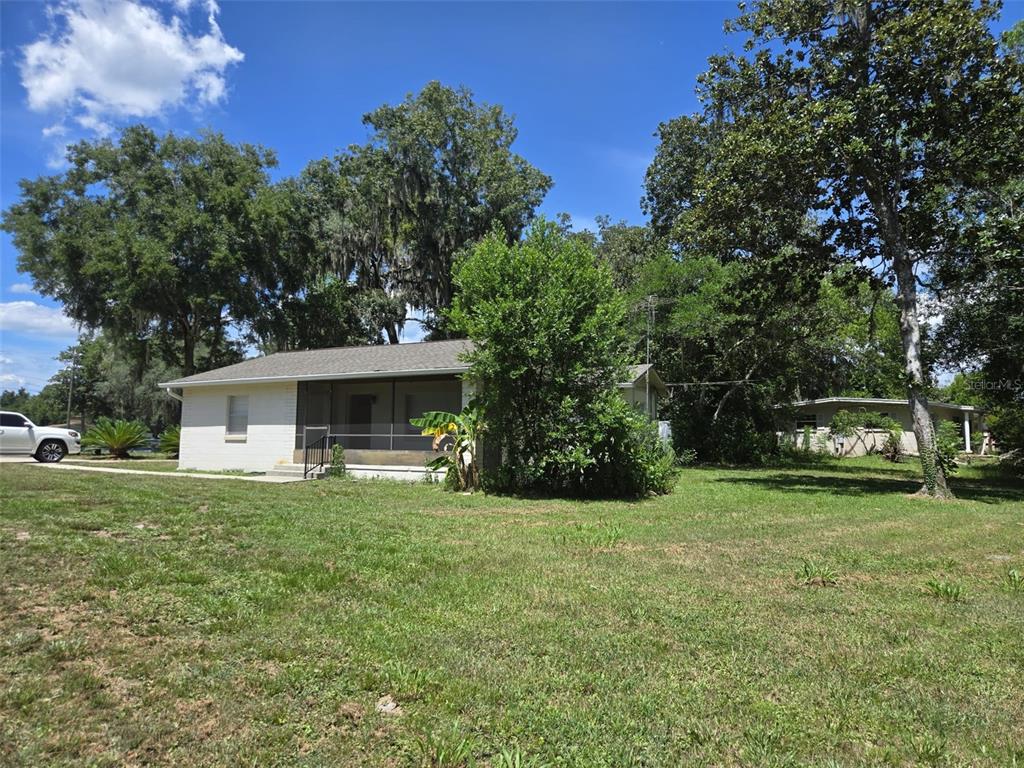 A single-story white house with a screened-in front porch sits on a large grassy lot — 659 N KEPLER ROAD, DELAND, FL