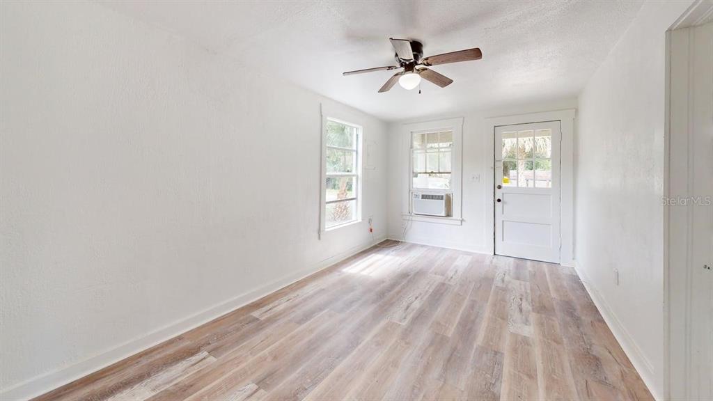 An empty room features white walls, wood-look flooring, a ceiling fan, and a glass-paneled door — 738 WOOD STREET UNIT 1, DELAND, FL