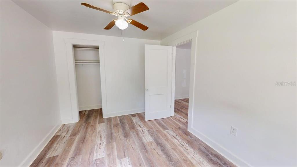 A bedroom features white walls, wood-look flooring, a ceiling fan, and an open closet — 738 WOOD STREET UNIT 1, DELAND, FL