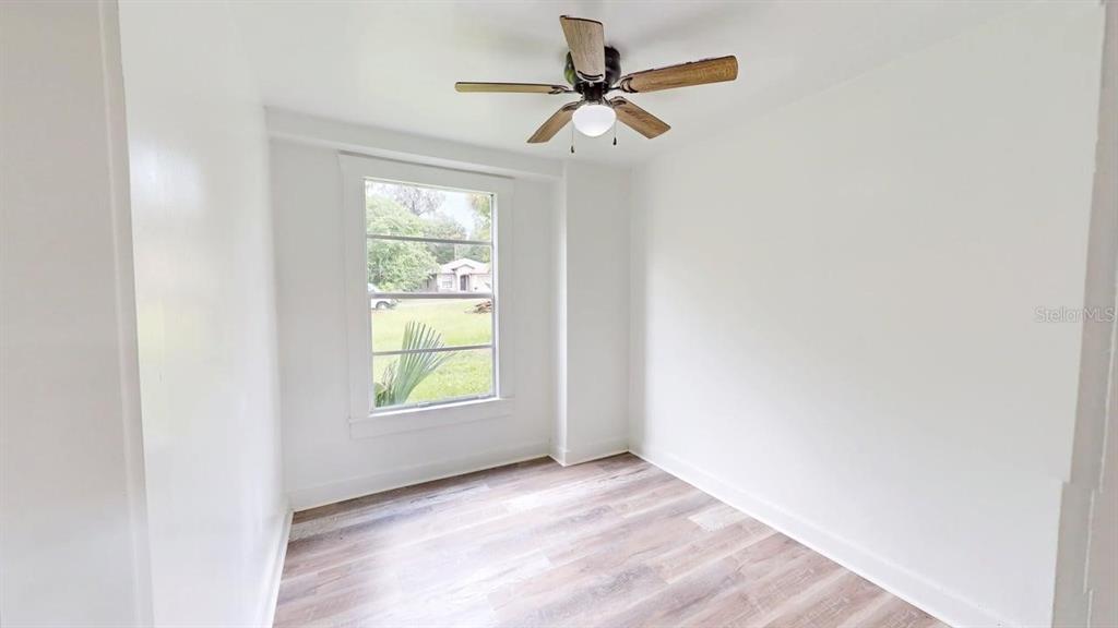 A small, empty room with white walls, wood-look flooring, a ceiling fan, and one window — 738 WOOD STREET UNIT 1, DELAND, FL
