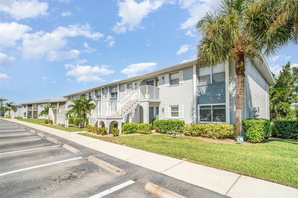 A two-story apartment building with a white exterior, palm trees, and a parking lot — 25050 SANDHILL BOULEVARD UNIT A4, PUNTA GORDA, FL