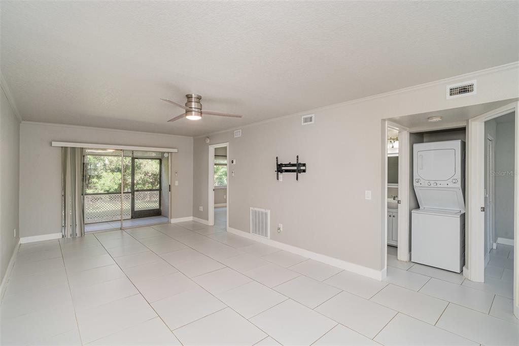 A bright living room features light tile flooring, a ceiling fan, and a stacked laundry unit — 25050 SANDHILL BOULEVARD UNIT A4, PUNTA GORDA, FL