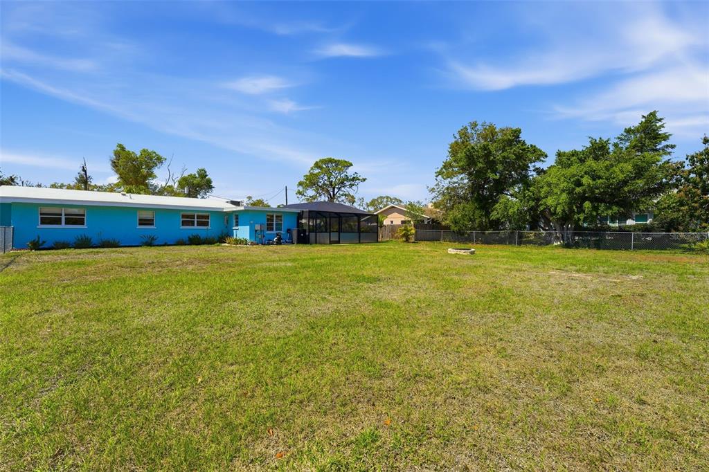 A bright blue house with a screened-in patio sits behind a large, grassy backyard — PALMETTO STREET, NOKOMIS, FL