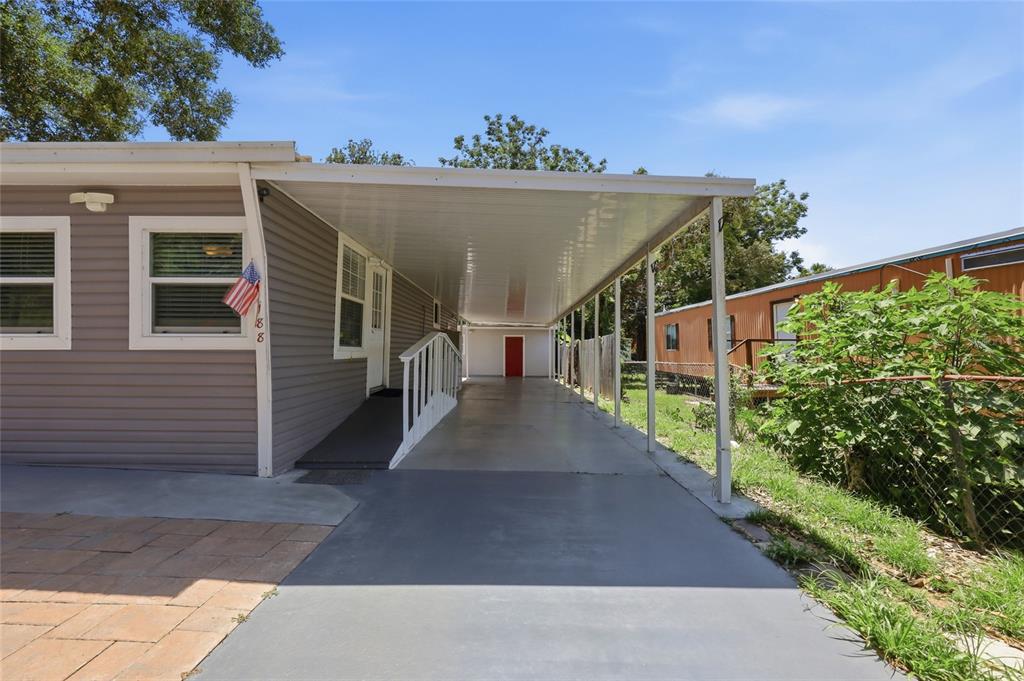 A gray mobile home features a long covered carport and a wheelchair ramp entrance — 188 MOBILE AVENUE, ALTAMONTE SPRINGS, FL