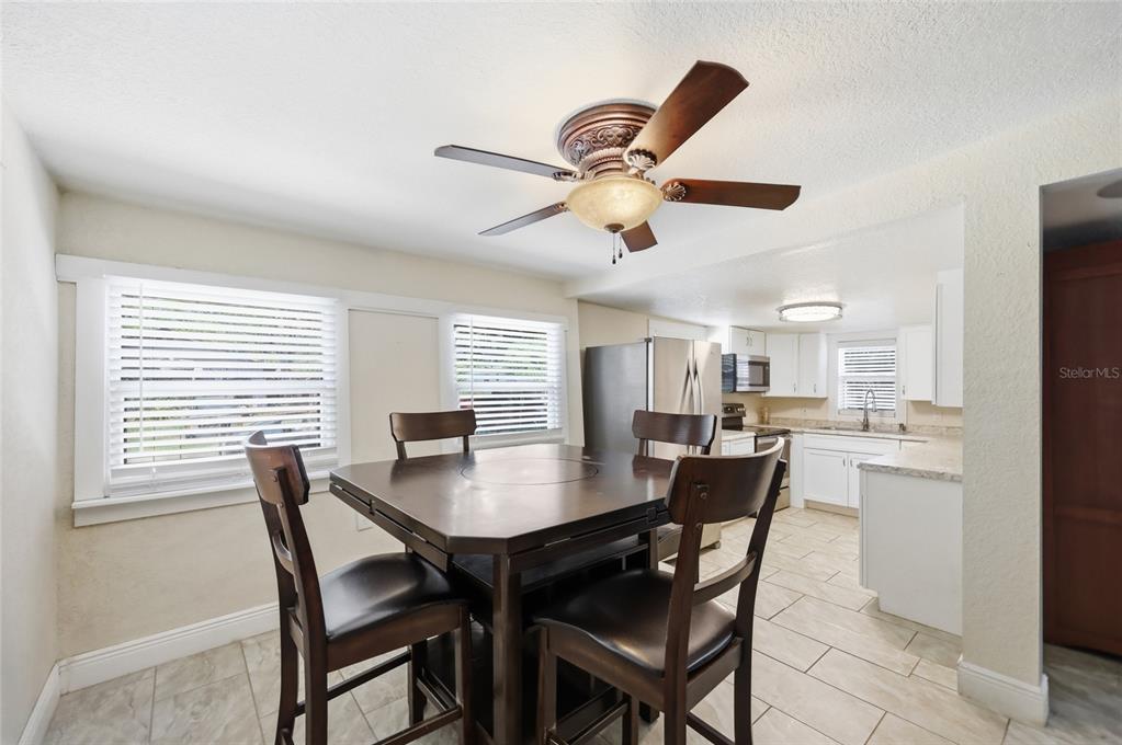 A dining area with a dark wood table and chairs sits adjacent to a white kitchen — 188 MOBILE AVENUE, ALTAMONTE SPRINGS, FL