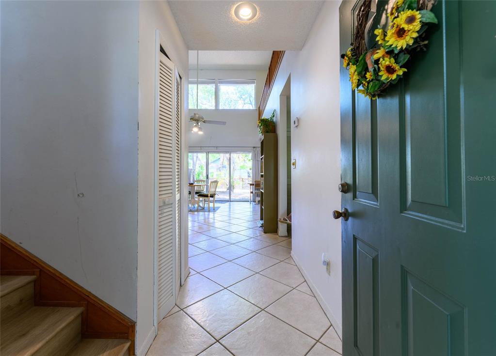 An entryway with tiled floors leads to a living area with high ceilings and windows — 4004 CROSSROADS PLACE, CASSELBERRY, FL