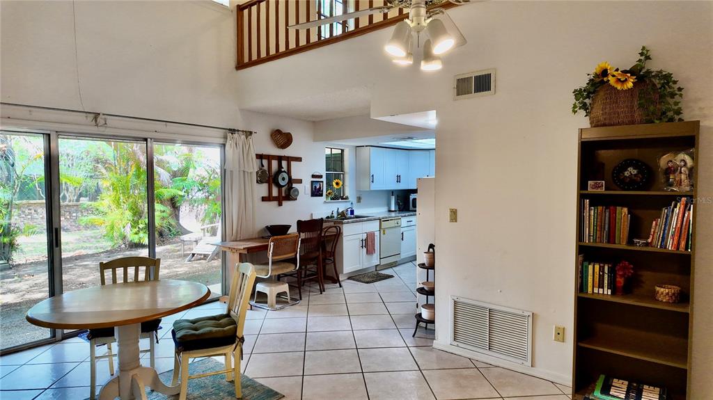 A dining area with a round table, tiled floors, and an adjacent kitchen with white cabinets — 4004 CROSSROADS PLACE, CASSELBERRY, FL