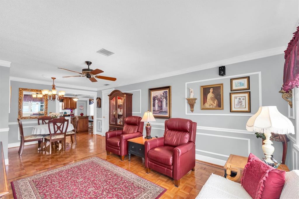 A living room with red leather recliners, a dining area, and hardwood parquet flooring — 6915 VERSAILLES N, PINELLAS PARK, FL