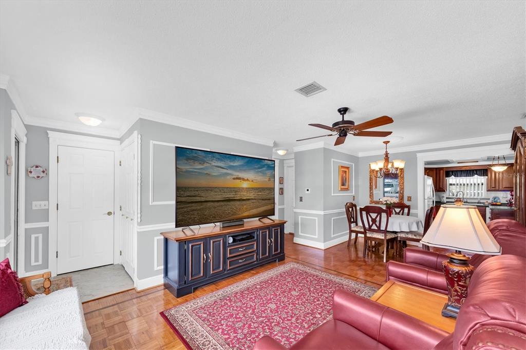 A living room features a television on a dark console, red rug, and dining area — 6915 VERSAILLES N, PINELLAS PARK, FL
