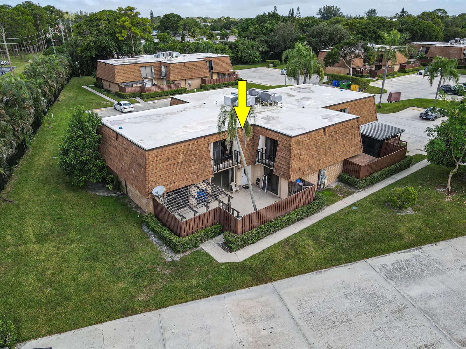 An aerial view shows a two-story brown building with a fenced patio and palm tree — 2406 24th Lane, FL 33463, FL