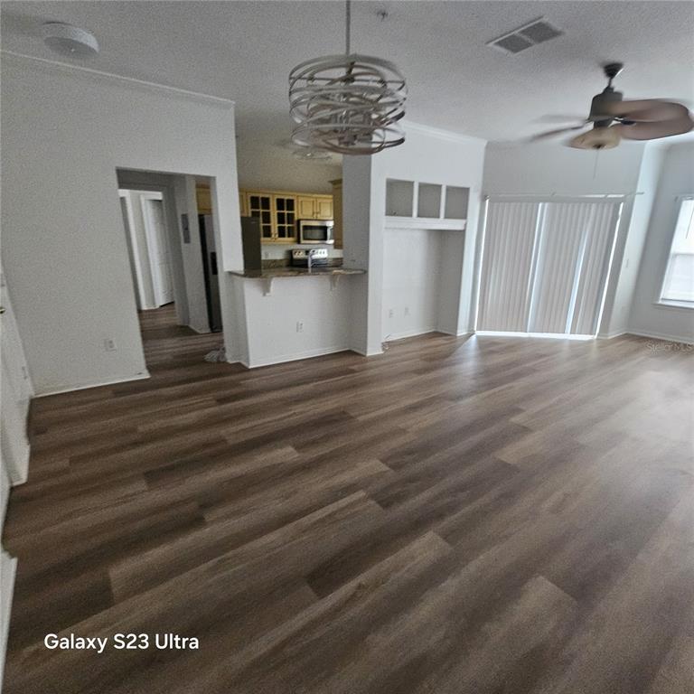 A living room with wood-look flooring, a ceiling fan, a chandelier, and an open kitchen — 3561 CONROY ROAD UNIT 220, ORLANDO, FL