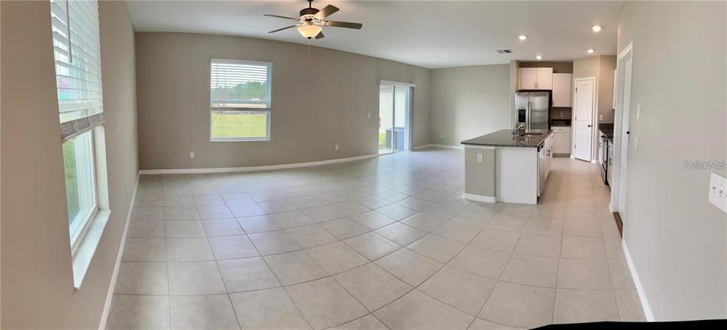 An open-concept living area features light tile flooring, a kitchen island, and a ceiling fan — 31454 BARREL WAVE WAY, WESLEY CHAPEL, FL