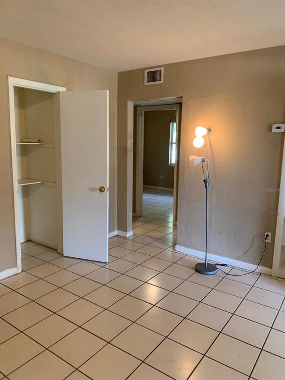 A room with beige tile flooring, a white closet door, and a standing floor lamp — 21266 COULTON AVENUE, PORT CHARLOTTE, FL