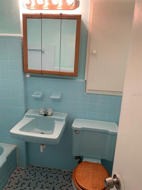 A bathroom features light blue tiled walls, a matching sink and toilet, and a wooden cabinet — 21266 COULTON AVENUE, PORT CHARLOTTE, FL