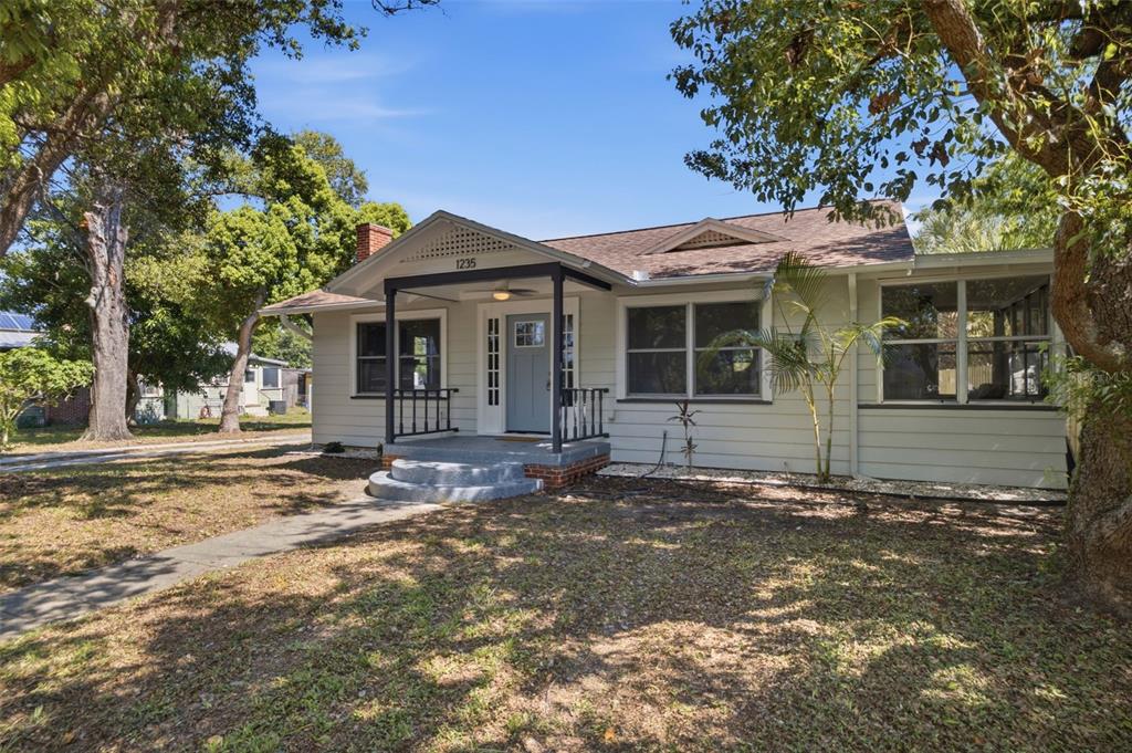 A light-colored, single-story house with a front porch and a large tree in the yard — 1235 IDLEWILD DRIVE, CLEARWATER, FL
