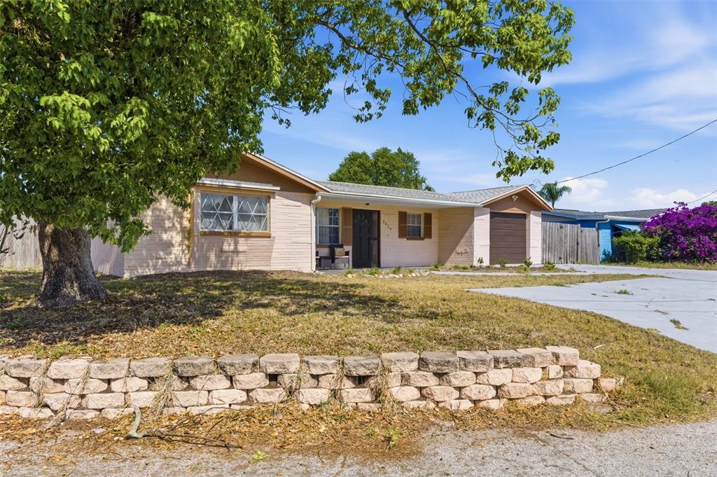 A single-story house with a brick facade, a front lawn, and a stone retaining wall — 8829 EILEEN DRIVE, PORT RICHEY, FL