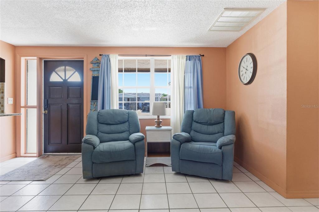 A living room features two blue recliners, a side table, and a front door — 8829 EILEEN DRIVE, PORT RICHEY, FL