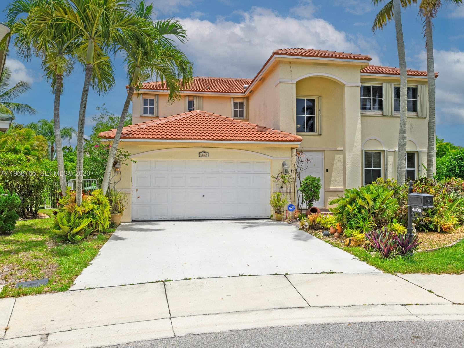 A two-story suburban house features a tiled roof, a white garage door, and palm trees — 4209 Pinewood Ln, Weston FL 33331, WESTON, FL