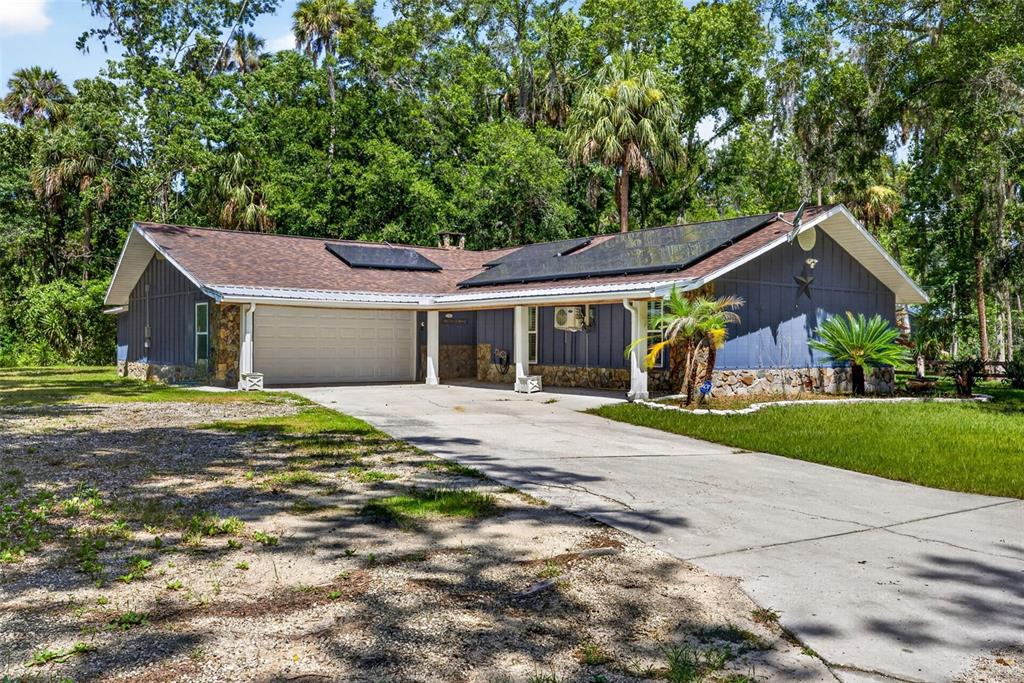 A blue house with a stone base, solar panels, and a concrete driveway — 4600 S LEWOODS DRIVE, HOMOSASSA, FL