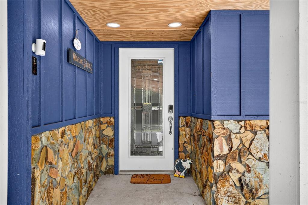 A front entryway features blue board-and-batten siding, stone veneer, and a white glass-paneled door — 4600 S LEWOODS DRIVE, HOMOSASSA, FL
