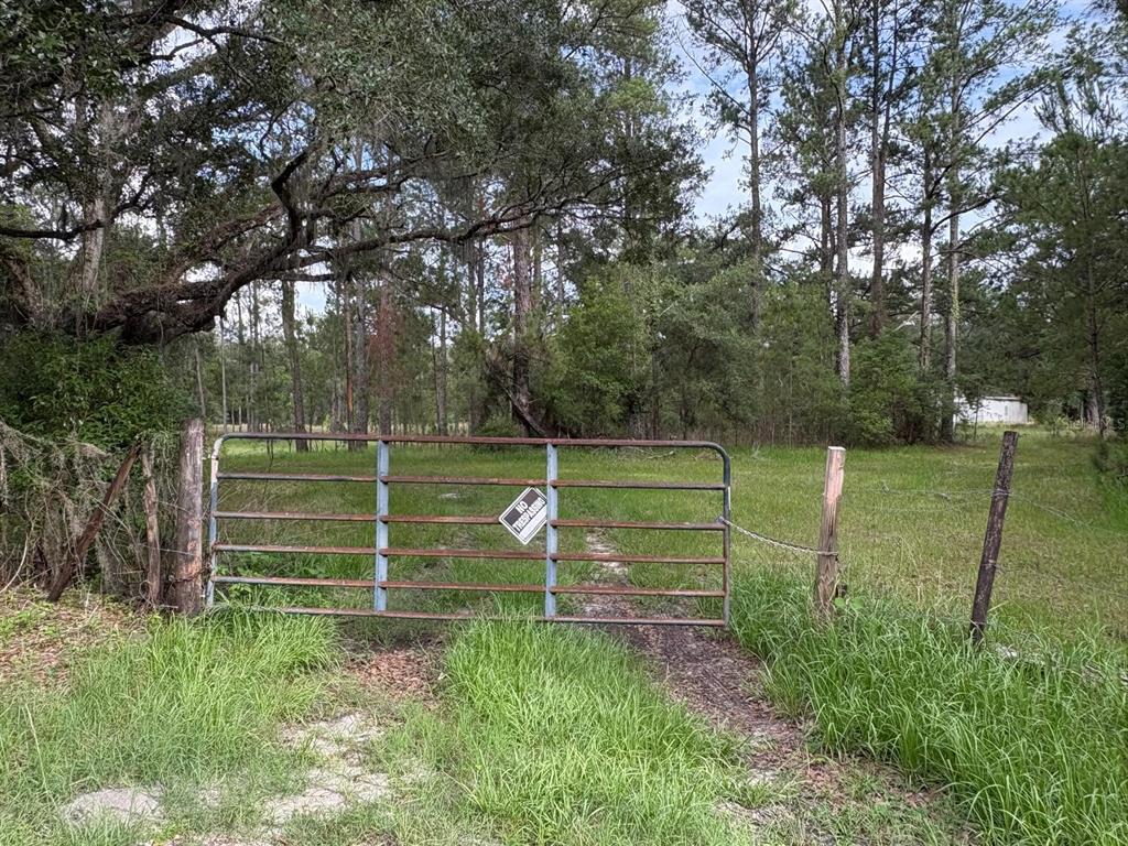 A metal gate with a no trespassing sign blocks a dirt path into a wooded lot — 0 BROAD STREET, BROOKSVILLE, FL