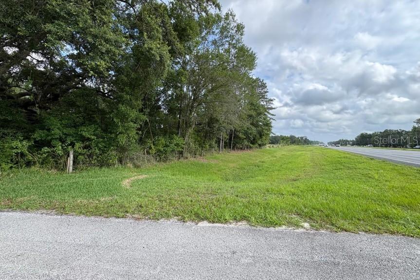 A grassy lot sits adjacent to a wooded area and a paved highway — 0 BROAD STREET, BROOKSVILLE, FL