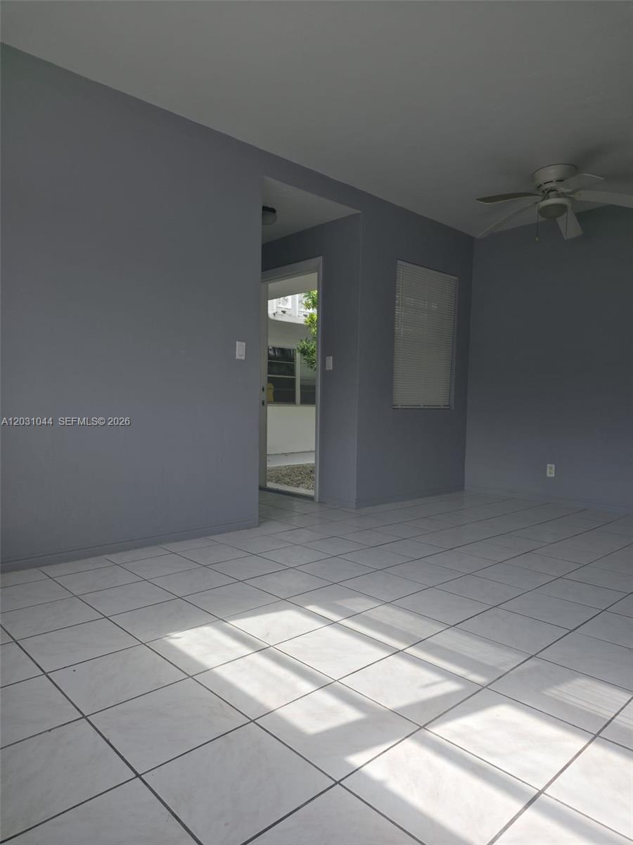 A room with light gray walls, white tiled floors, a ceiling fan, and a doorway — 1610 Liberty St # 1, Hollywood FL 33020, HOLLYWOOD, FL