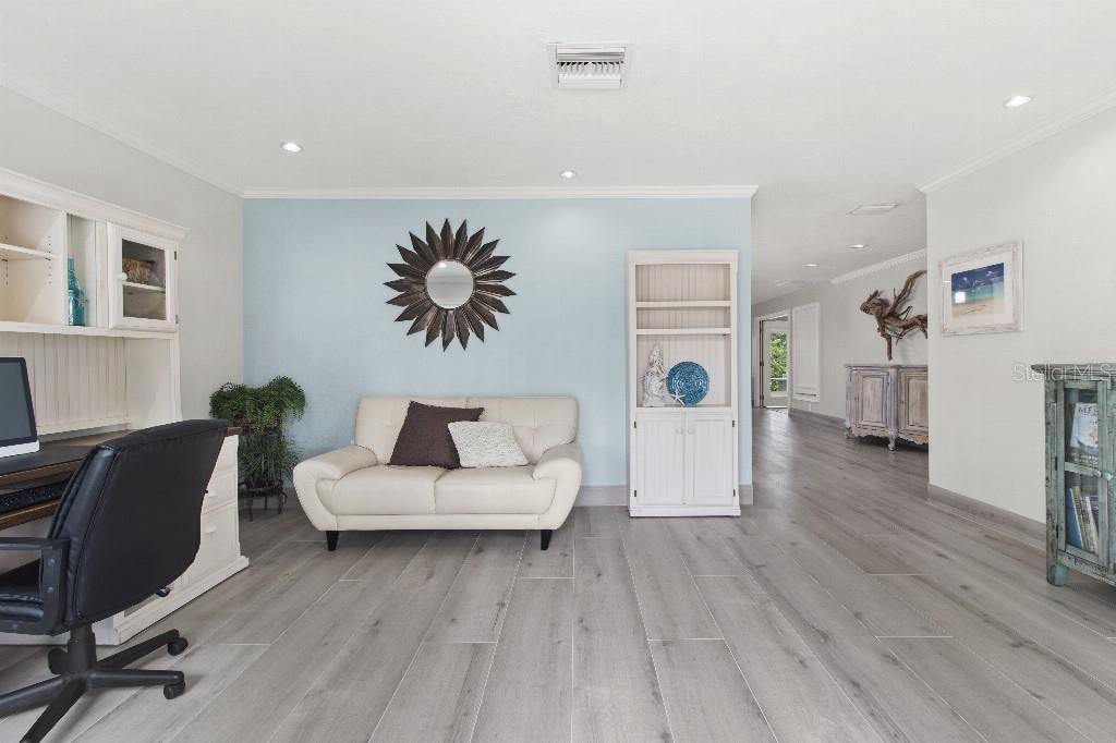 A home office features a white sofa, a desk, and light wood-look flooring — 810 25TH AVENUE W, PALMETTO, FL